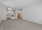 Thumbnail 11 of 27 - the living room and kitchen of an empty house with white walls and carpet