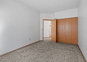 Thumbnail 7 of 27 - a bedroom with a door to a closet and a carpeted floor