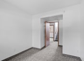 Thumbnail 15 of 43 - a bedroom with white walls and a door to a hallway with stairs