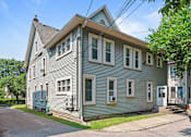 Thumbnail 30 of 67 - a gray house with white siding on the corner of a street