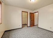 Thumbnail 12 of 23 - A room with a carpeted floor and a wooden door.