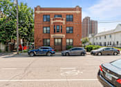 Thumbnail 28 of 67 - a brick building with cars parked in front of it on a street