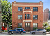 Thumbnail 27 of 67 - a brick building with cars parked in front of it