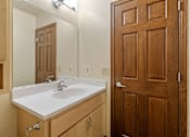 Thumbnail 9 of 23 - A bathroom with a sink, mirror, and wooden door.