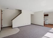 Thumbnail 26 of 57 - an empty living room with white walls and a kitchen with a stove and a door