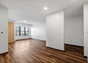 Thumbnail 9 of 26 - a living room with white walls and wood flooring and a window