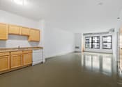 Thumbnail 24 of 30 - an empty kitchen and living room with white walls and wood cabinets