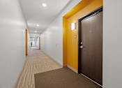 Thumbnail 27 of 53 - a hallway with white walls and a wooden floor and a brown door