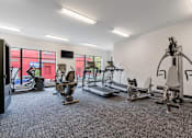 Thumbnail 29 of 35 - a gym with weights and cardio equipment in a building with windows