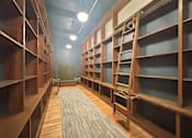 Thumbnail 19 of 24 - a library with wooden shelves and a rug