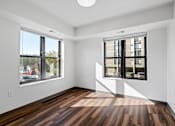 Thumbnail 10 of 26 - a living room with two windows and wood floors