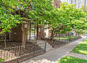 Thumbnail 2 of 25 - a sidewalk in front of a brick building with trees