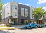 Thumbnail 41 of 52 - a brick building with two cars parked in front of it