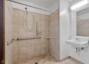Thumbnail 39 of 43 - a bathroom with a shower and a sink and a mirror