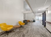 Thumbnail 46 of 55 - a long corridor with yellow chairs and tables and white walls