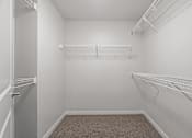 Thumbnail 18 of 53 - spacious walk in closet with hanging racks and white walls and carpeted flooring