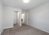 Thumbnail 19 of 53 - a bedroom with white walls and carpet and a door to a closet