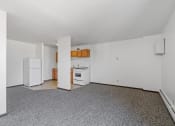 Thumbnail 34 of 51 - an empty living room with a kitchen with a stove and refrigerator