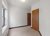 Thumbnail 56 of 67 - a bedroom with white walls and a wooden door and a window