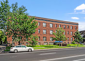 Thumbnail 16 of 25 - a red brick building with a white car parked in front of it