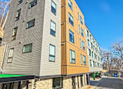 Thumbnail 20 of 22 - A modern apartment building with a mix of wood and stone exterior.