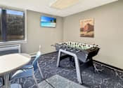 Thumbnail 14 of 17 - A foosball table is in the middle of a room with a TV and a picture on the wall.