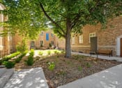 Thumbnail 28 of 45 - a courtyard with a tree and benches in front of a brick building