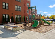 Thumbnail 24 of 26 - a playground with a slide and a bench in front of a building