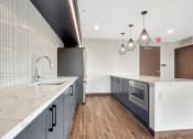 Thumbnail 9 of 36 - A modern kitchen in the Skydeck Lounge with dark wood floors and white countertops.