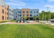 Thumbnail 32 of 36 - A playground with a slide is in front of apartment buildings.