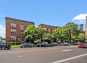 Thumbnail 11 of 25 - a city street with cars parked in front of a brick building