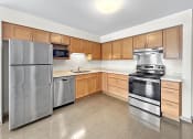 Thumbnail 7 of 52 - an empty kitchen with stainless steel appliances and wooden cabinets