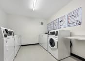 Thumbnail 14 of 36 - A laundry room with a sign on the wall and several washing machines.