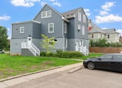 Thumbnail 18 of 27 - a blue house with a black car parked in front of it