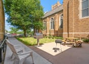 Thumbnail 26 of 45 - a patio outside of a church with a grill and picnic table