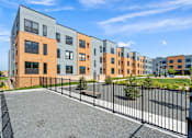 Thumbnail 36 of 36 - A row of modern apartment buildings with a black fence in front.