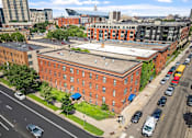 Thumbnail 4 of 25 - an aerial view of an old brick building with a white roof on a city street