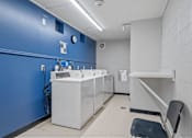 Thumbnail 20 of 23 - a public restroom with a blue wall and white washing machines