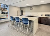 Thumbnail 4 of 17 - A kitchen with a bar area and blue chairs.