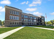 Thumbnail 24 of 24 - a brick building with a lawn and an flag