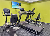 Thumbnail 21 of 22 - A gym with a yellow wall and a television screen showing a beach.