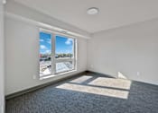 Thumbnail 10 of 22 - a living room with a large window and gray carpet