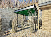 Thumbnail 18 of 22 - A treehouse with a green roof and a sign that says "TREEHOUSE" on the side of a building.