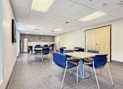 Thumbnail 6 of 17 - A conference room with a white table and blue chairs.