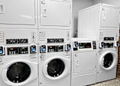Thumbnail 21 of 24 - a row of washers and dryers in a laundry room