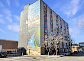 Thumbnail 2 of 17 - A large mural on the side of a building depicts a scene with birds and a body of water.
