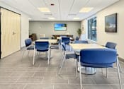 Thumbnail 5 of 17 - A conference room with blue chairs and a television on the wall.