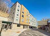 Thumbnail 2 of 22 - A modern building with a parking lot in front.