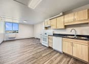 Thumbnail 9 of 17 - A kitchen with wooden floors and white appliances.
