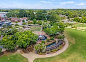 Thumbnail 29 of 47 - A large green park with a fountain and seating area.